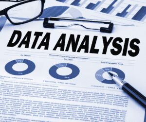 Printed report headed DATA ANALYSIS with pie charts and bar graphs, a pen and a pair of glasses resting on top