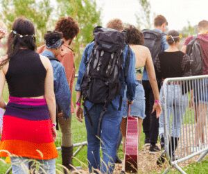 Festival-goers with backpacks and a guitar walking along a metal crowd barrier towards the site