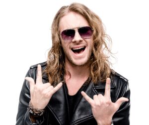 Long-haired man in sunglasses and a black leather jacket making rock horn gestures with both hands against a white background