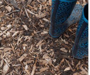 Blue patterned wellington boots standing in a thick layer of muddy wood chippings