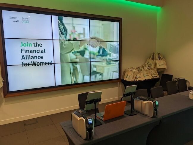 Exec stations in front of the Financial Alliance for Women welcome screen