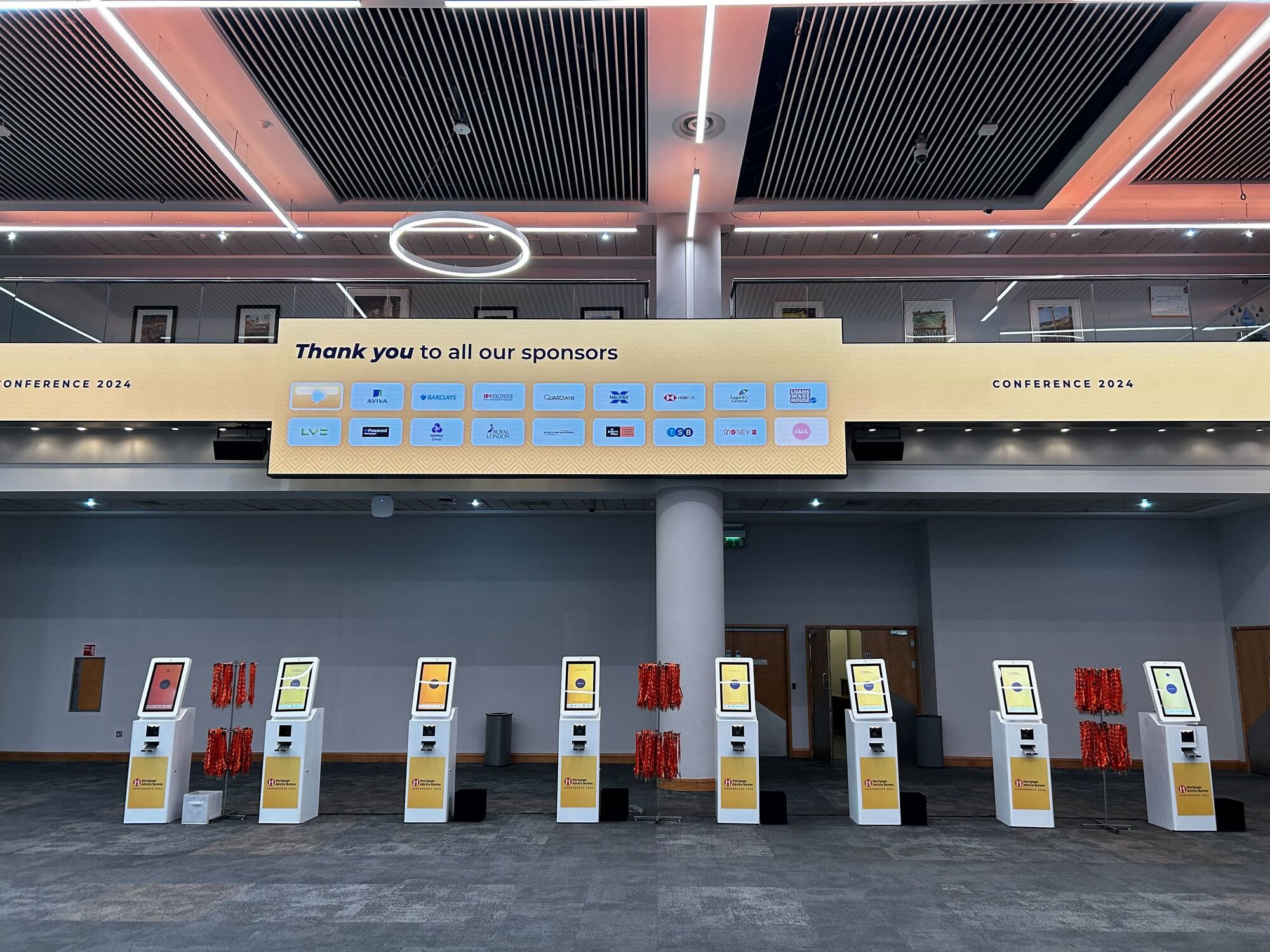Branded Max kiosks lined up beneath a sponsor thank-you screen