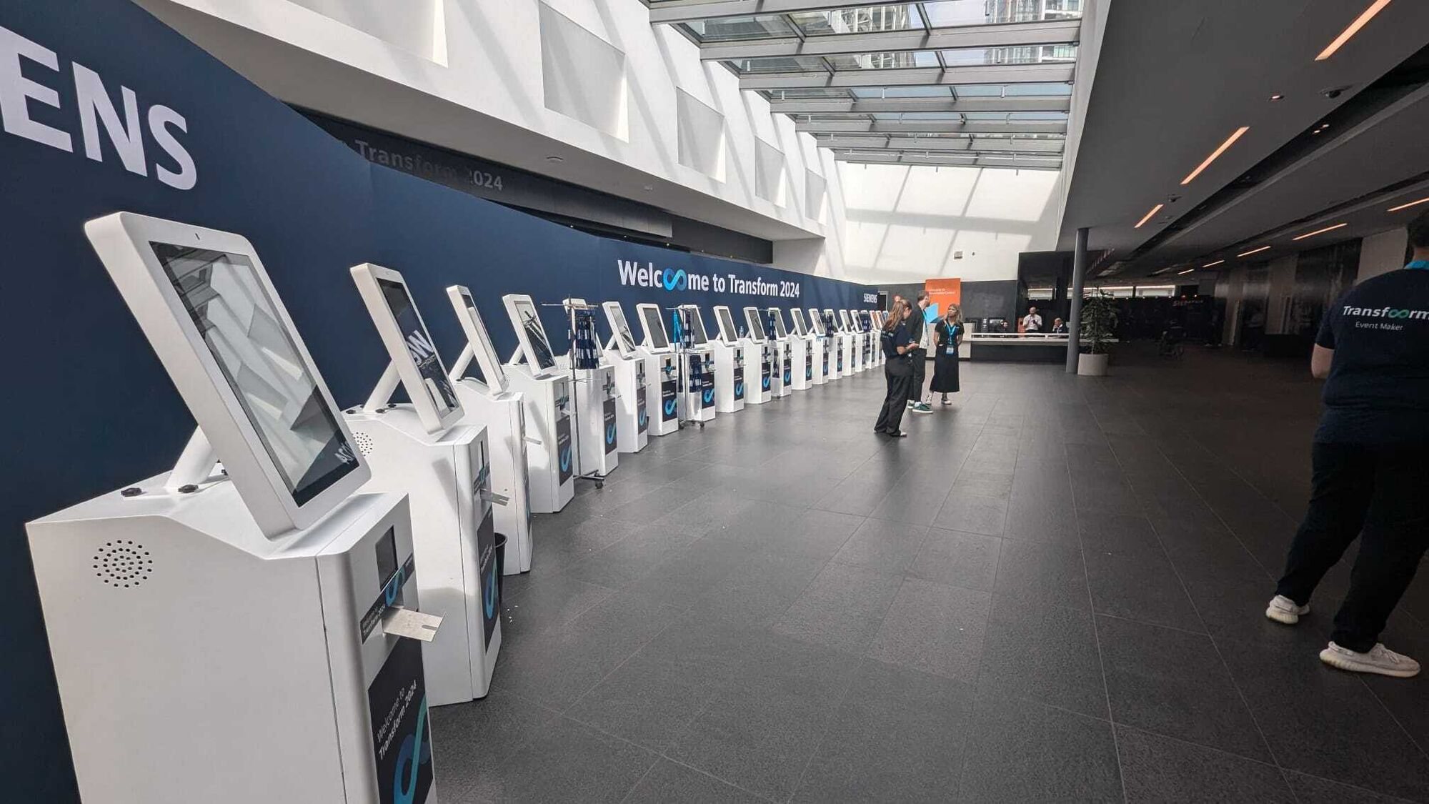 White Max kiosks lining the entrance wall at Transform 2024
