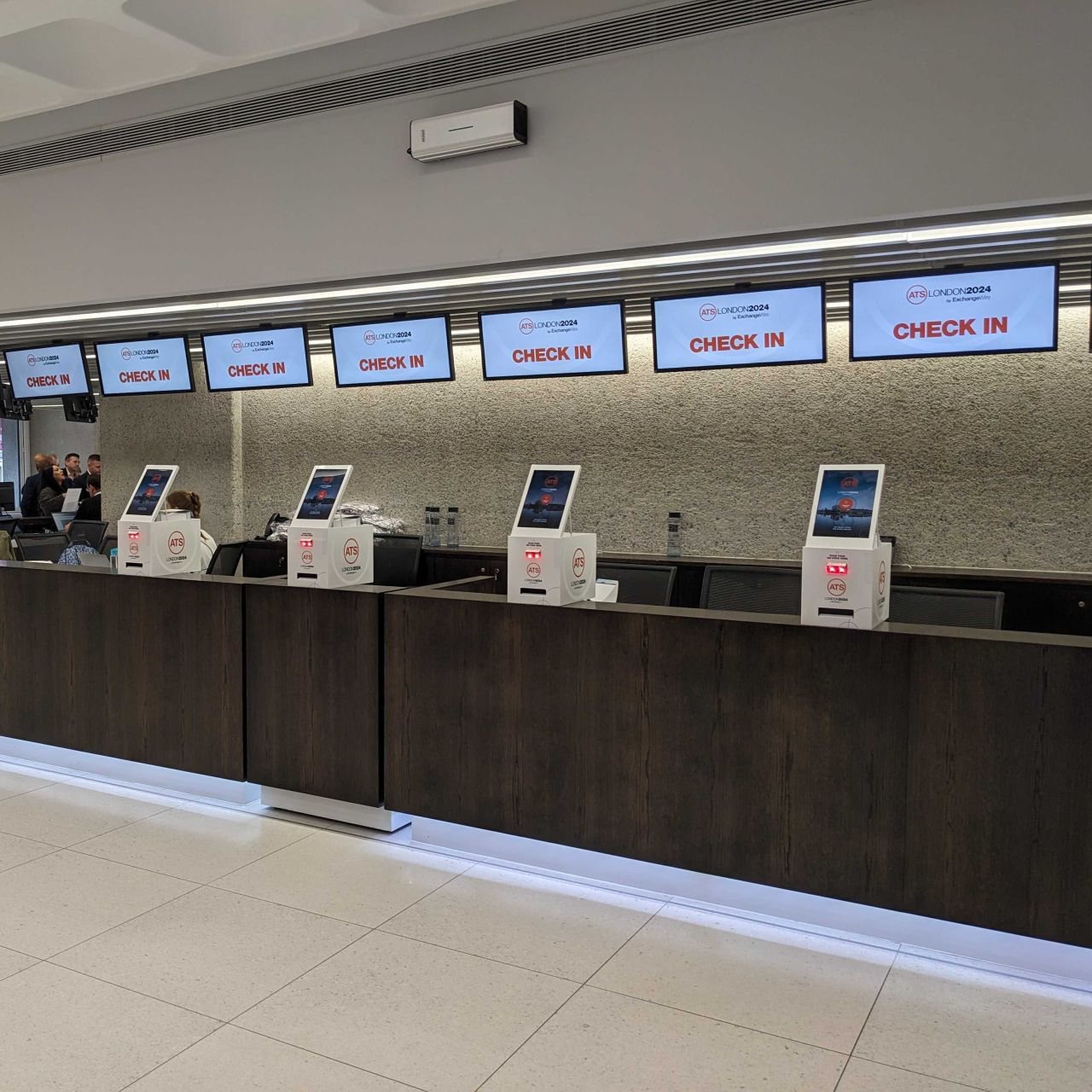 A row of branded Mini kiosks along the check-in counter at ATS London